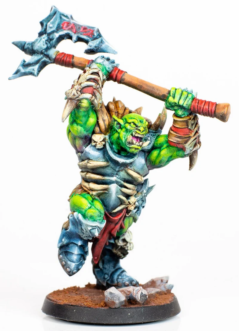Green orc tabletop miniature raising a jagged great axe