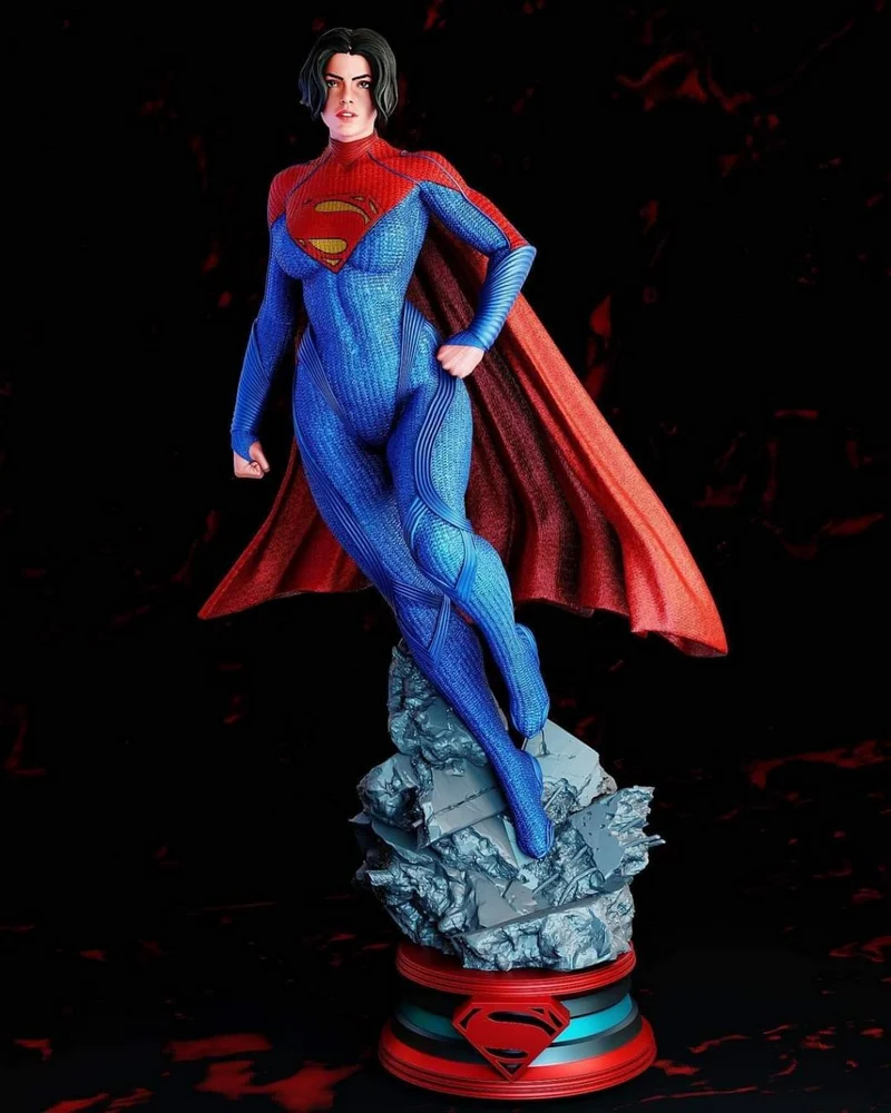 Supergirl statue in a blue suit and red cape on a rocky base