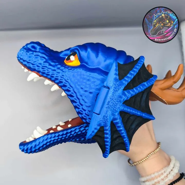 Blue dragon hand puppet with white teeth, dark wings, horns, and a yellow eye